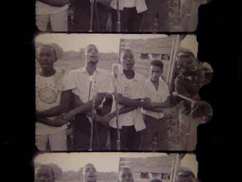 Image of a film reel from The Streets of Greenwood (1963) showing five young boys, arms crossed low over their torsos to interlock their hands with the person standing on either side of them. 