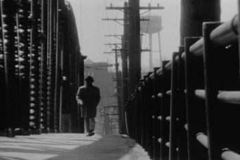 Photo of a man walking down a street lined with telephone polls from More than One Thing.