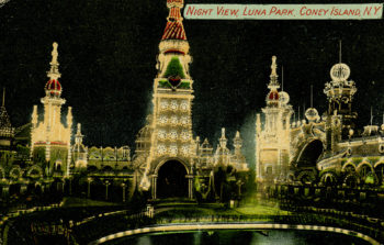 The front image of a postcard. Text on the image designates it as "Night view, Luna Park, Coney Island, NY" and the photo is of the towers and spires at Coney Island, brightly lit at night by a multitude of fairy-lights. 