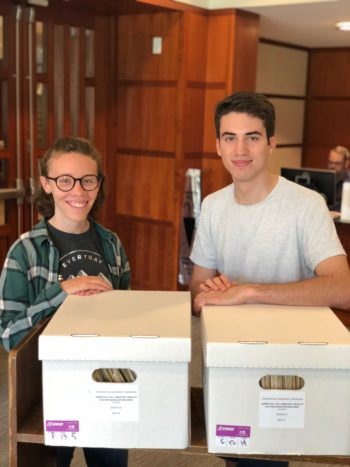 WUSTL undergraduates Natalie Hilmer and Jordan Dubin stand with boxes from the archive.