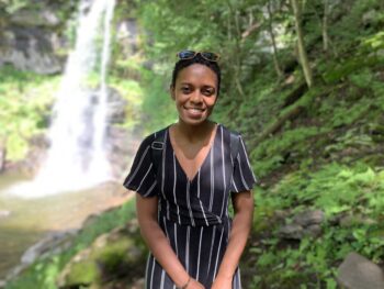 Photo of Ashley Jackson with a lush jungle and waterfall in the background. 