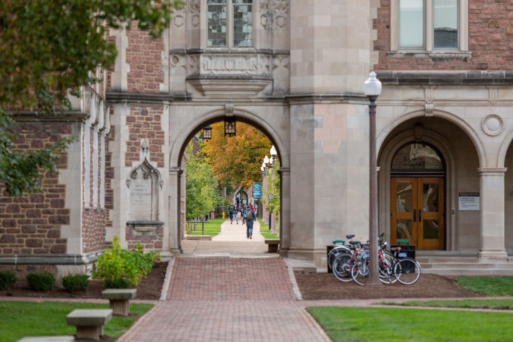 Decorative image of students walking through one of the many arches on campus. 