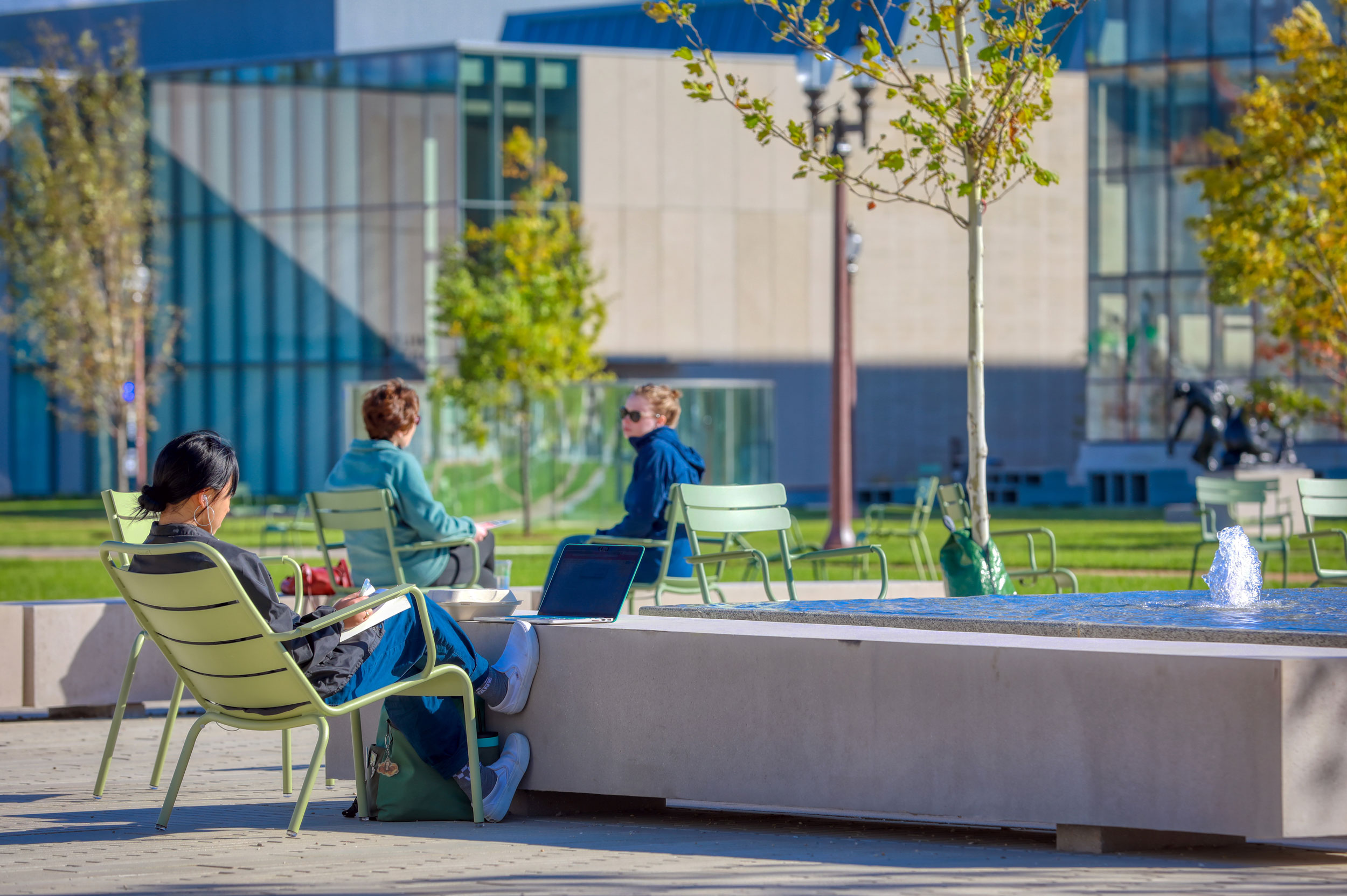 Students sitting and studying outside near a fountain.