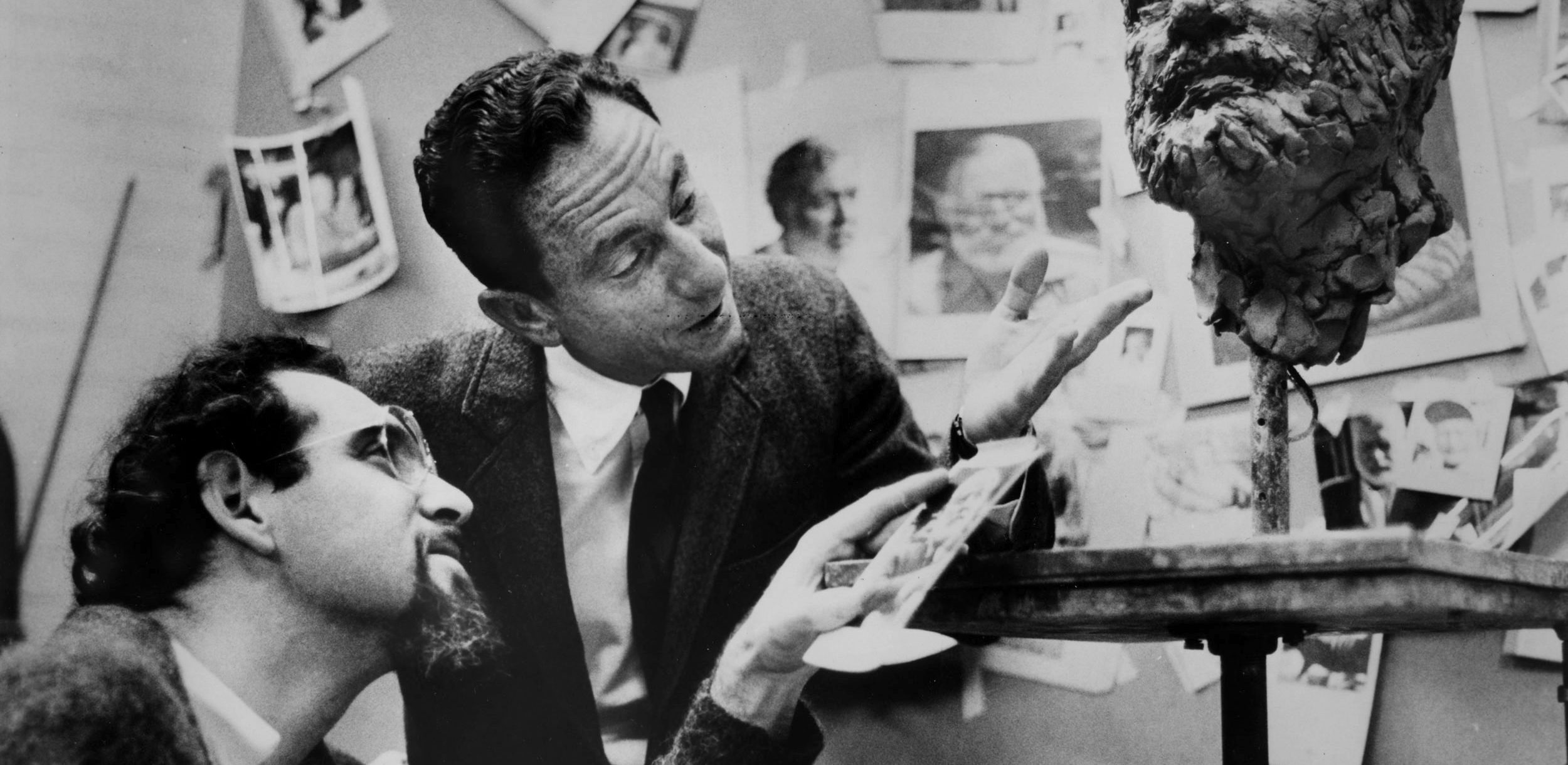 Two men inspecting a sculptor's work.