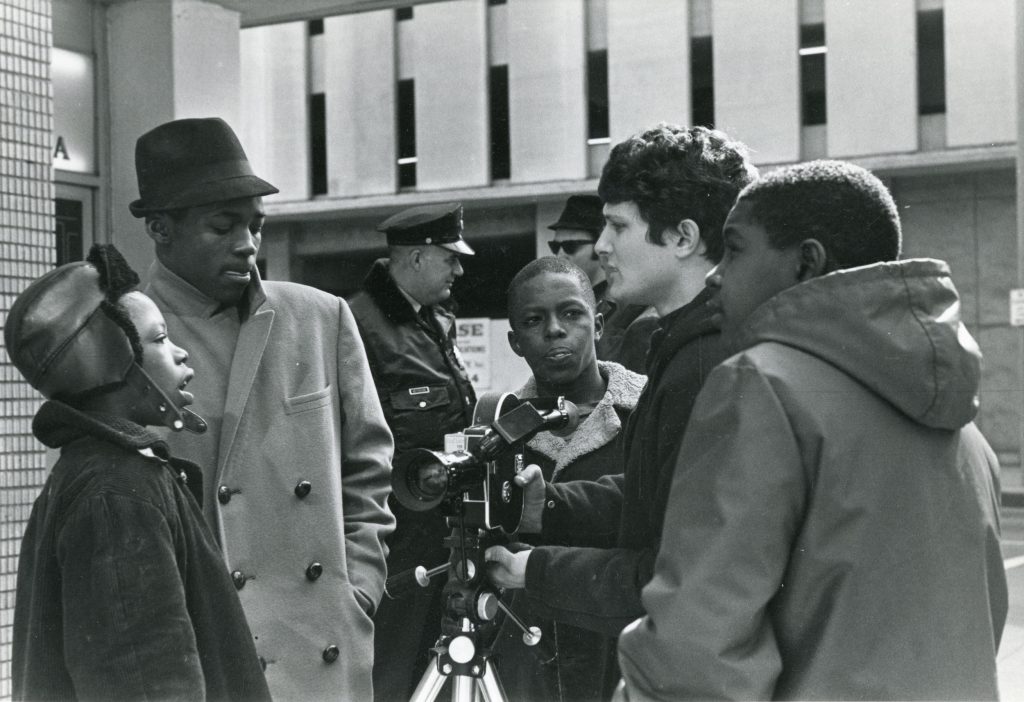 Four individuals featured in the More Than One Thing documentary gathered around Steve Carver and his camera. 