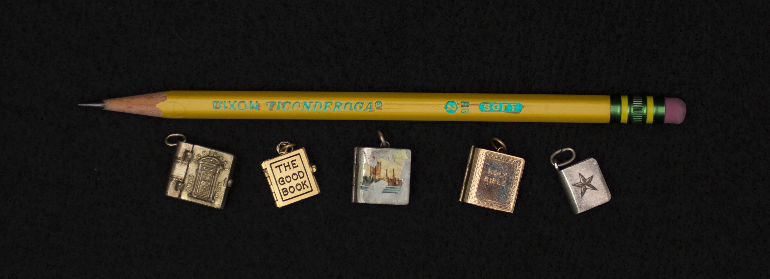 Five of the miniature books shown alongside a used #2 pencil. All five books fit along the length of the pencil with room to spare.