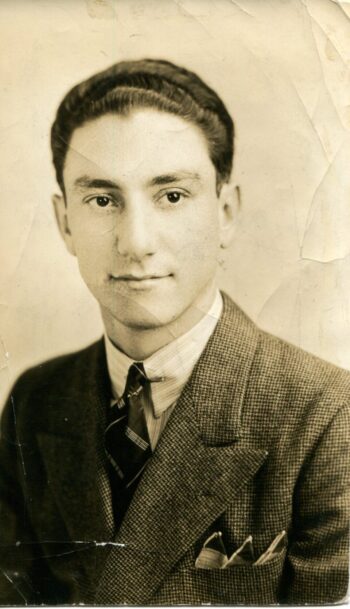 Photo portrait of A.E. Hotchner, who is wearing a collared button down with a tie beneath a suit jacket with a three peak folded pocket square in his suit pocket The photo is slightly wrinkled with age. 