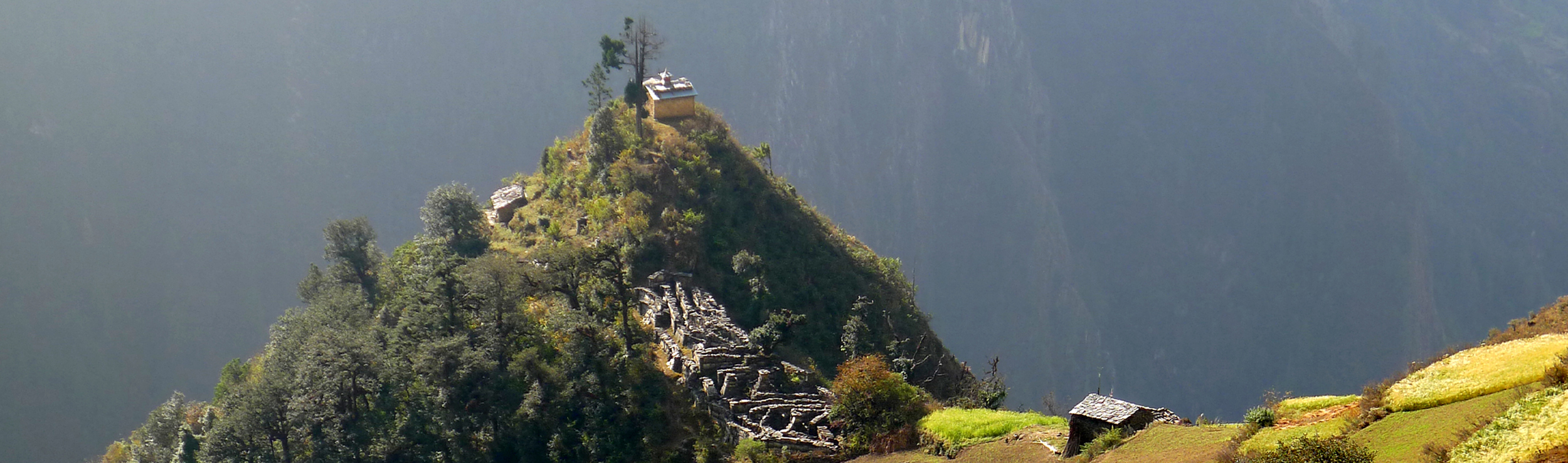 A small building sits on a mountain peak some distance away.