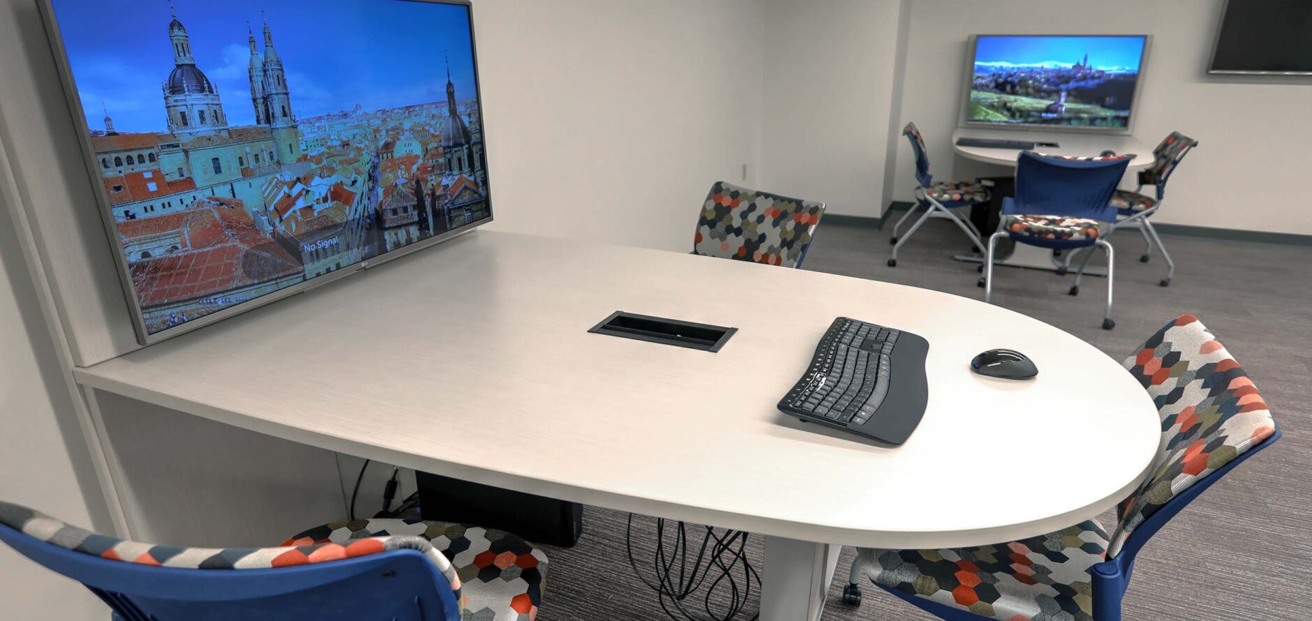 An empty table with chairs and a large screen within the Data Services Research Studio.