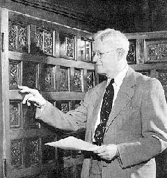 Image of Ernst C. Krohn examining rare books and carved wood panels. 