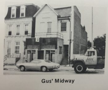 A nondescript two- or three-story building at the corner of a street. 