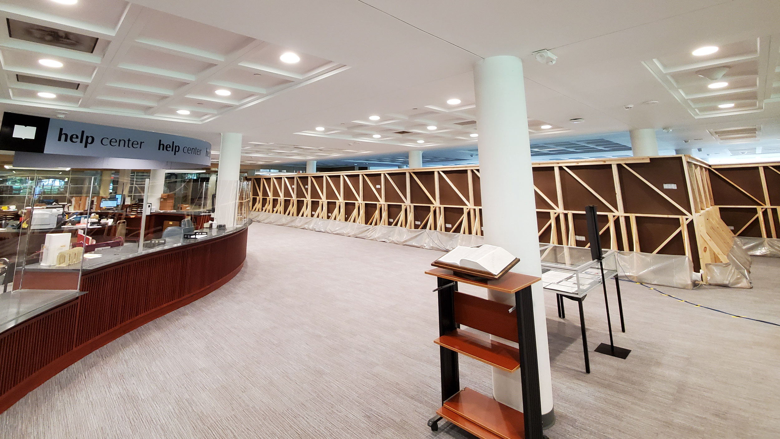 A photo of the empty lobby of the Olin Help Desk with a partition erected in the background separating usable space in the Library.