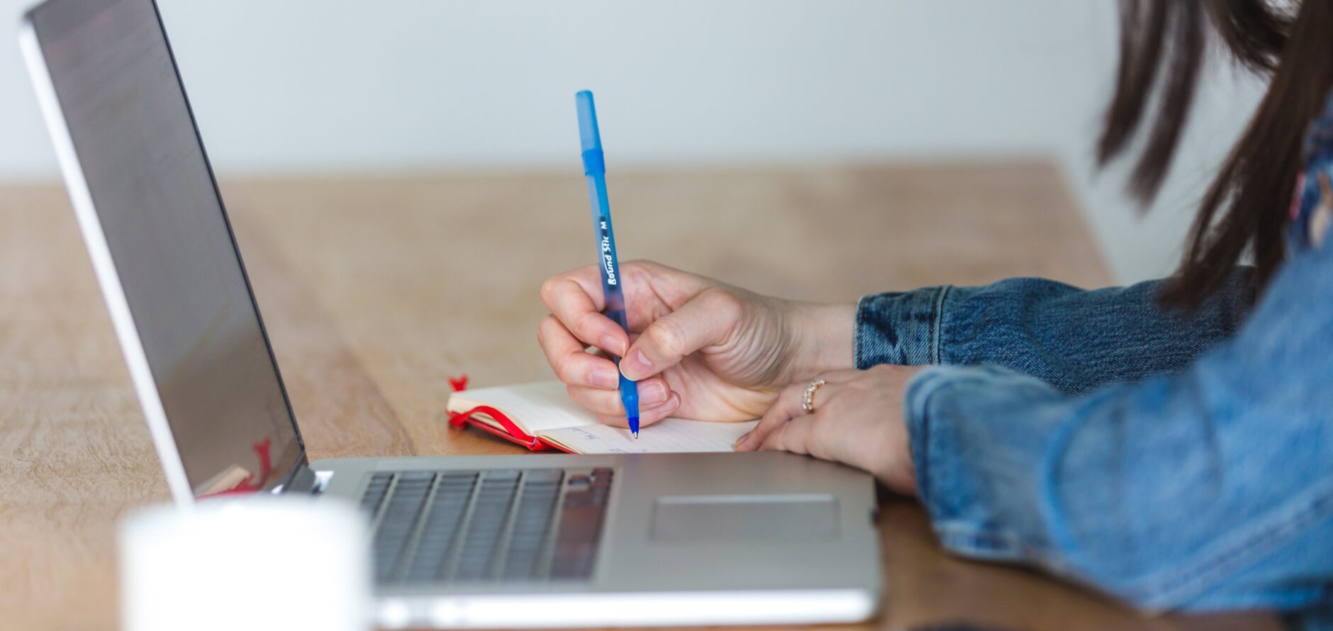 Stock image of a student studying with a laptop and notebook alongside them.