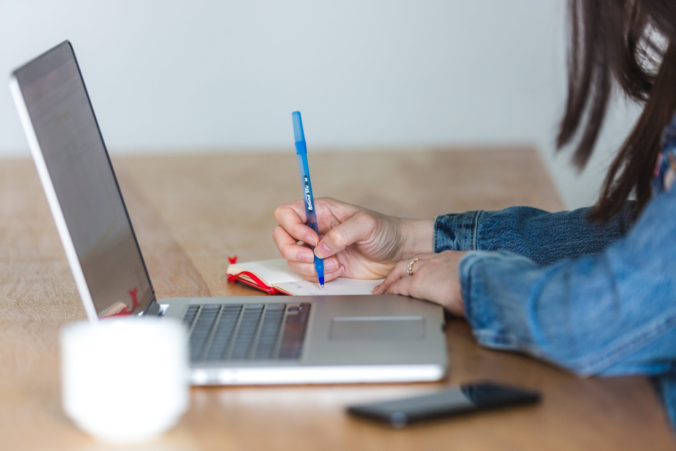 Stock image of a student studying with a laptop and notebook alongside them.