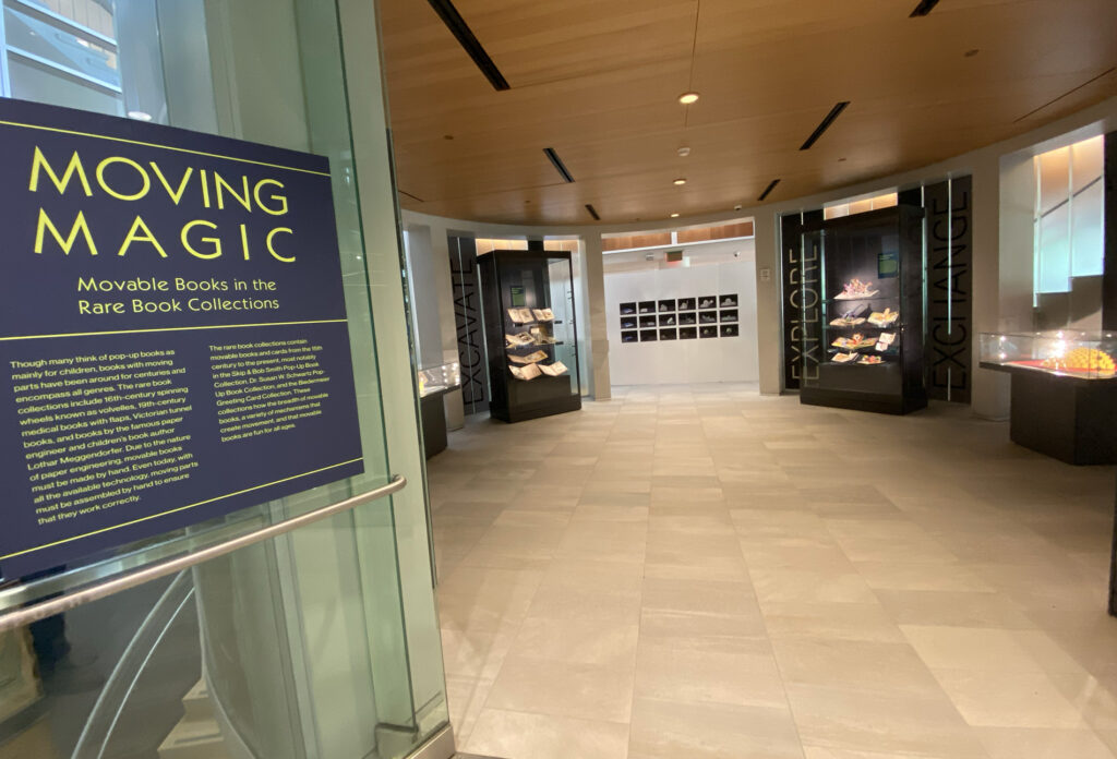 The image shows the exhibition plague for Moving Magic: Movable Books in the Rare Book Collections at the entrance to the Newman Tower of Collections and Exploration.