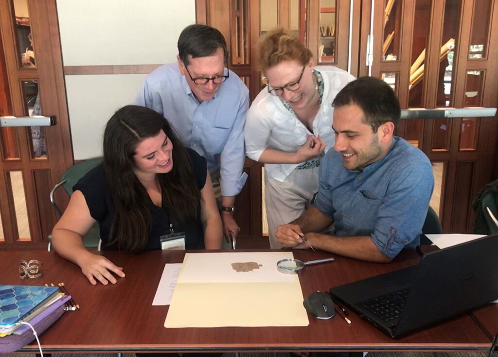 Four individuals are gathered around a piece from the papyri collection.