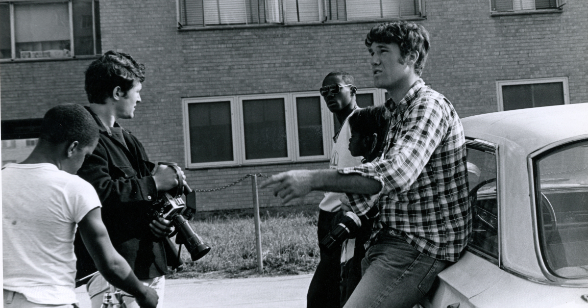 A black and white photo of a group of men and boys standing outside.