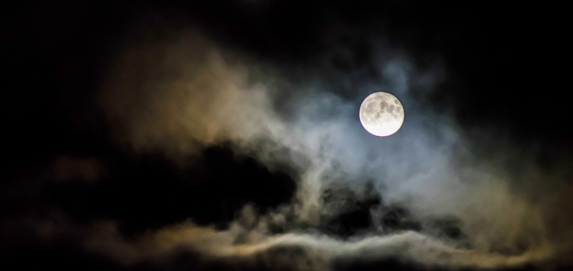 A photograph of a full moon on a cloudy night.