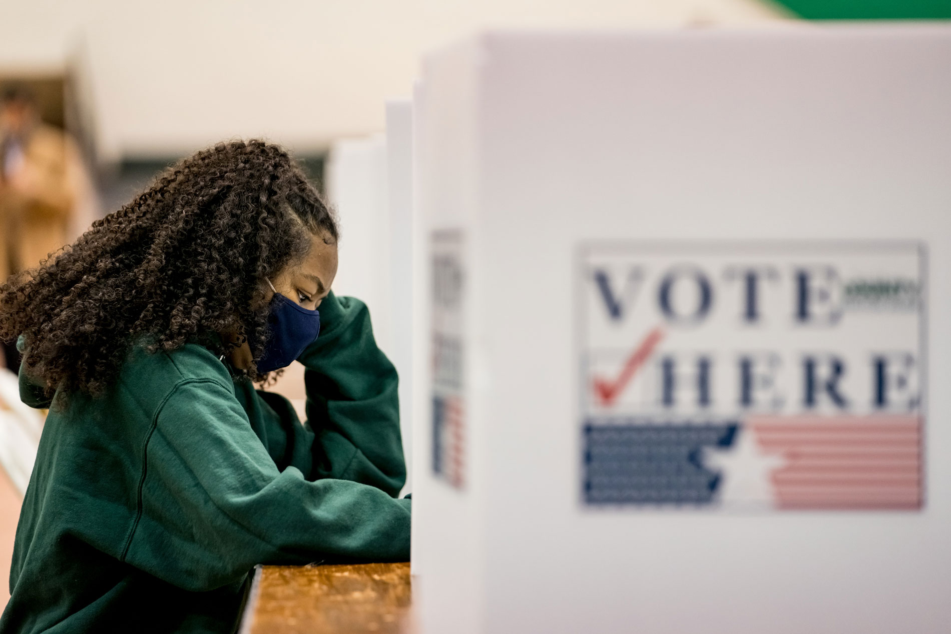 A student voting behind a privacy partition.