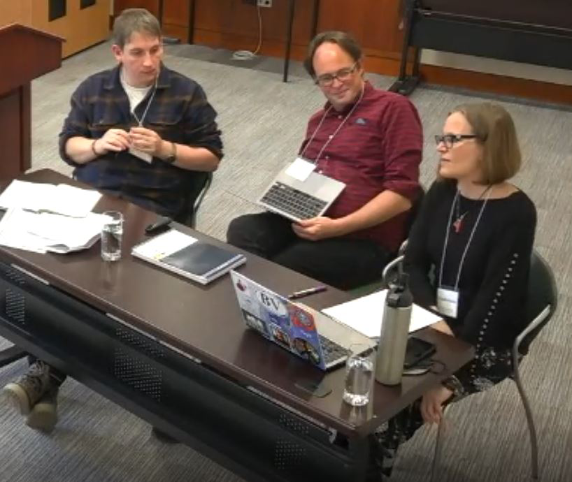 Three speakers sitting behind a table