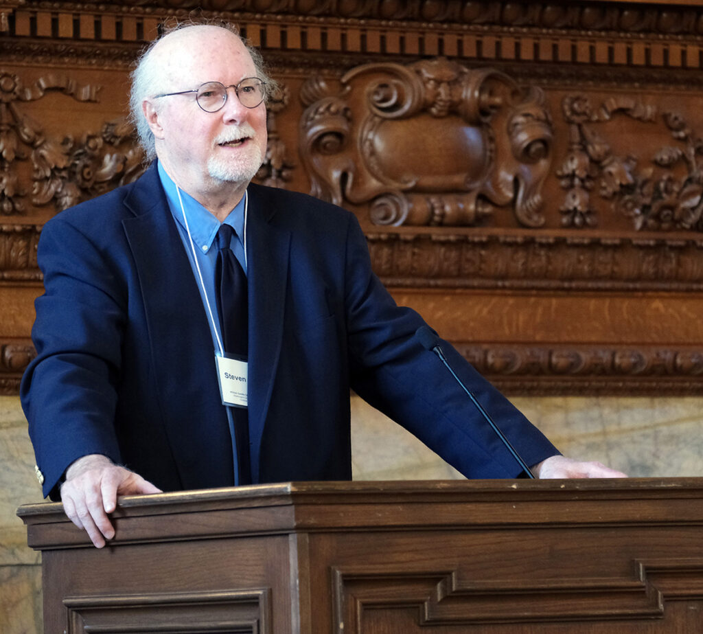 Man standing and speaking behind a lectern.