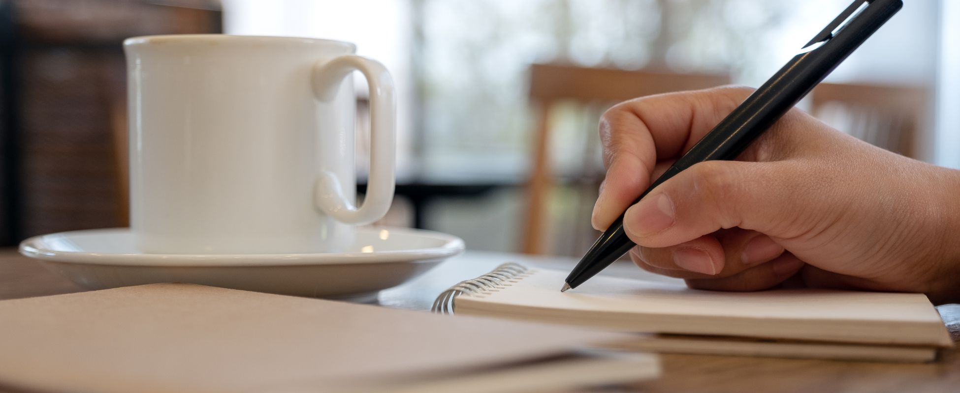 Person writing with a coffee.