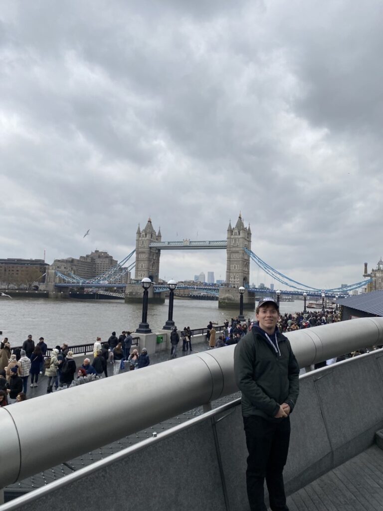 Man standing in front of Thames river and London Bridge.