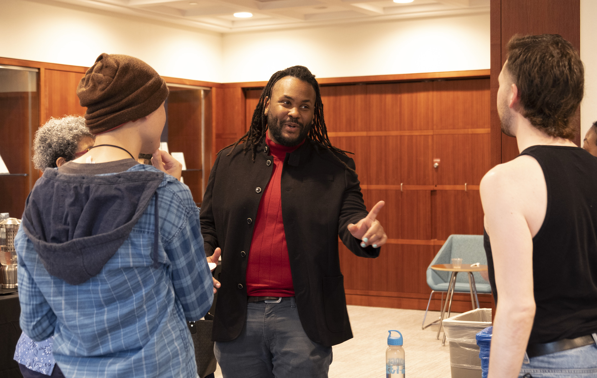 Poet Aaron Coleman conversing with guests in a room.