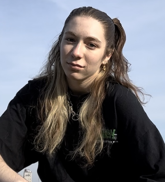 A woman in a black t-shirt against the blue backdrop of the sky.