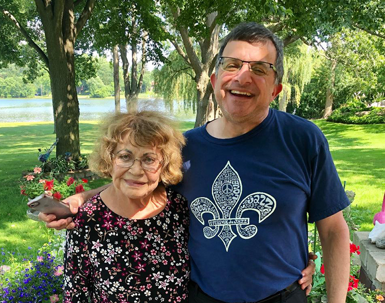 An elderly woman and a man smiling in a garden.