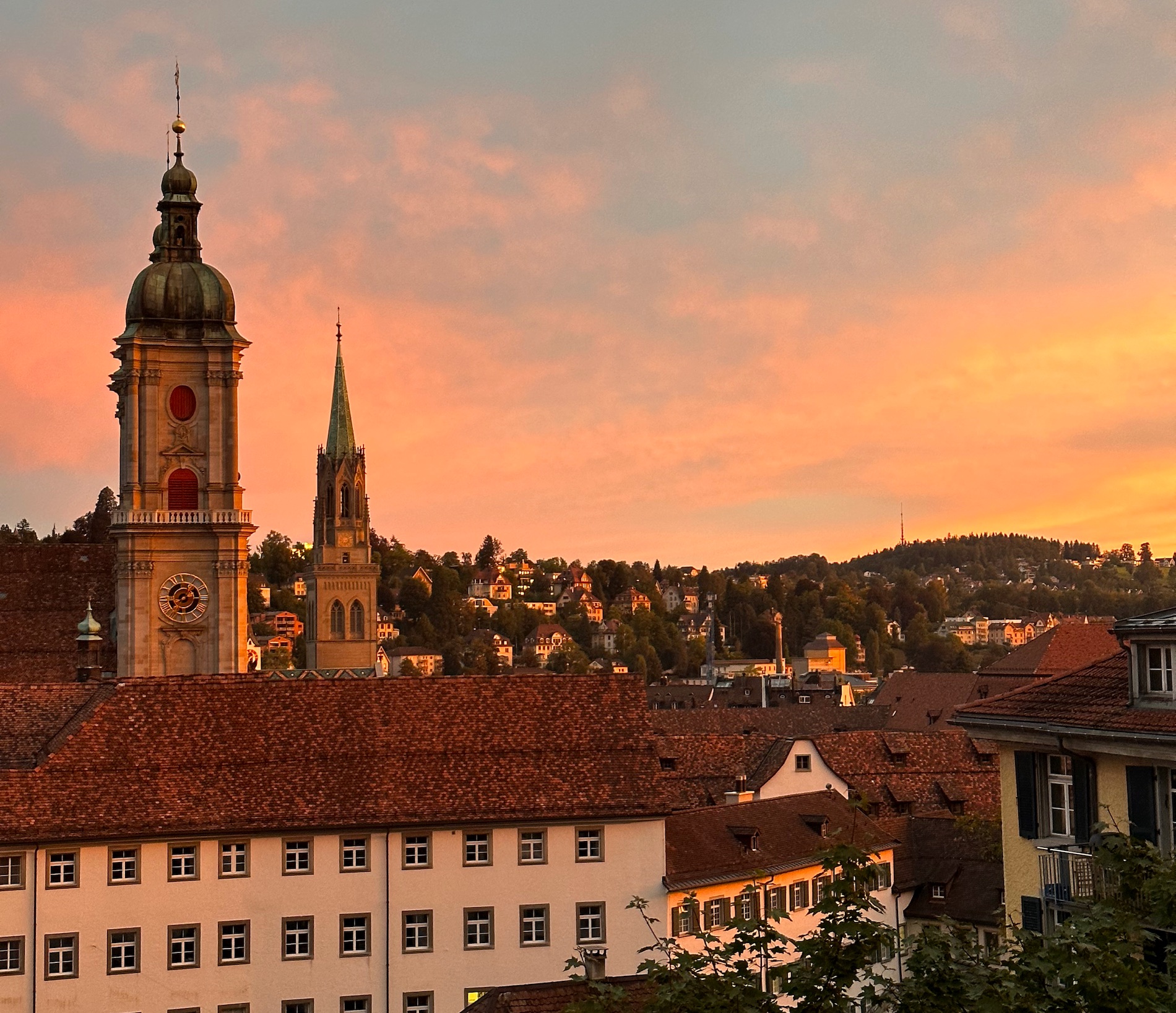 Tall spires rising above tiled buildings against the evening sky.