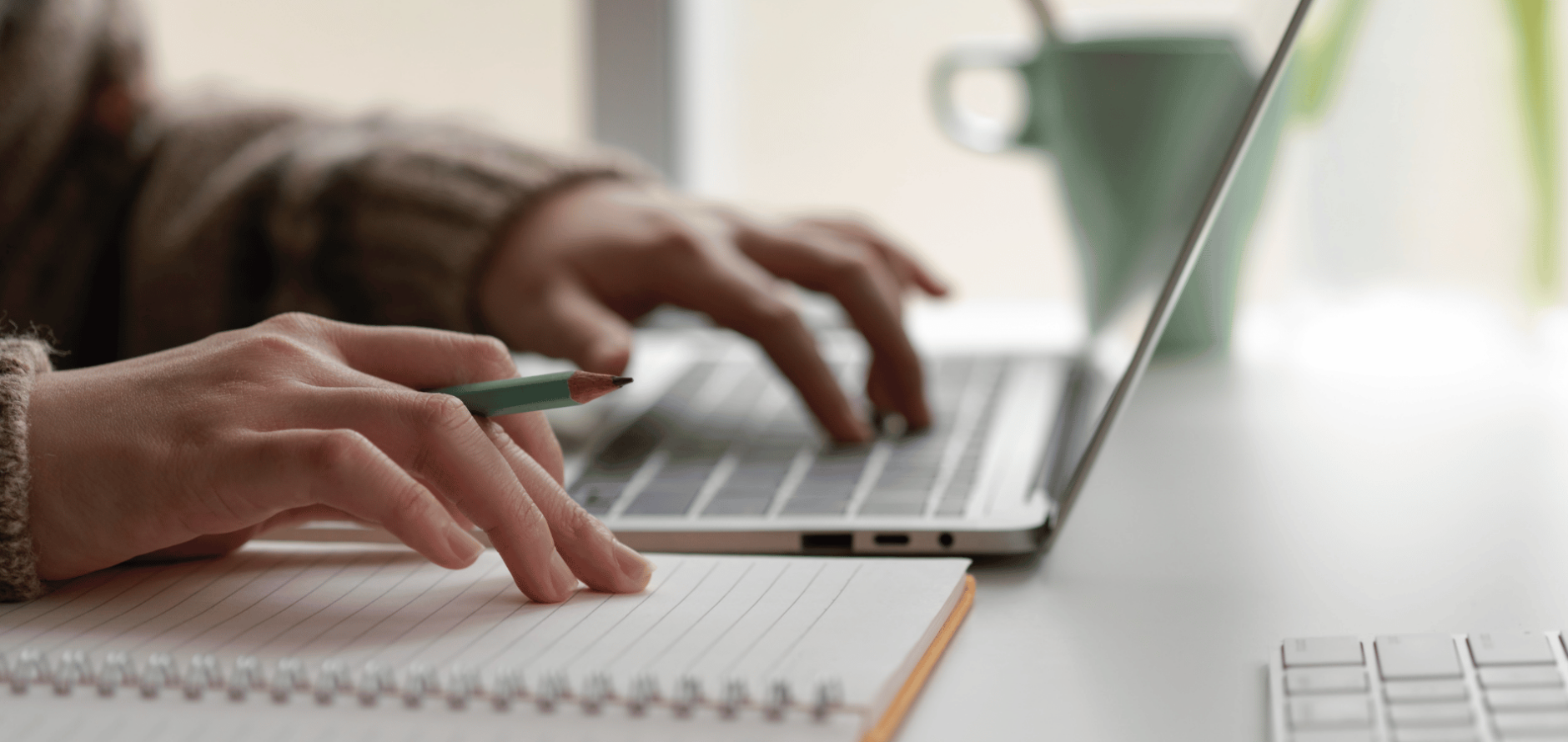 Person typing on laptop and taking notes