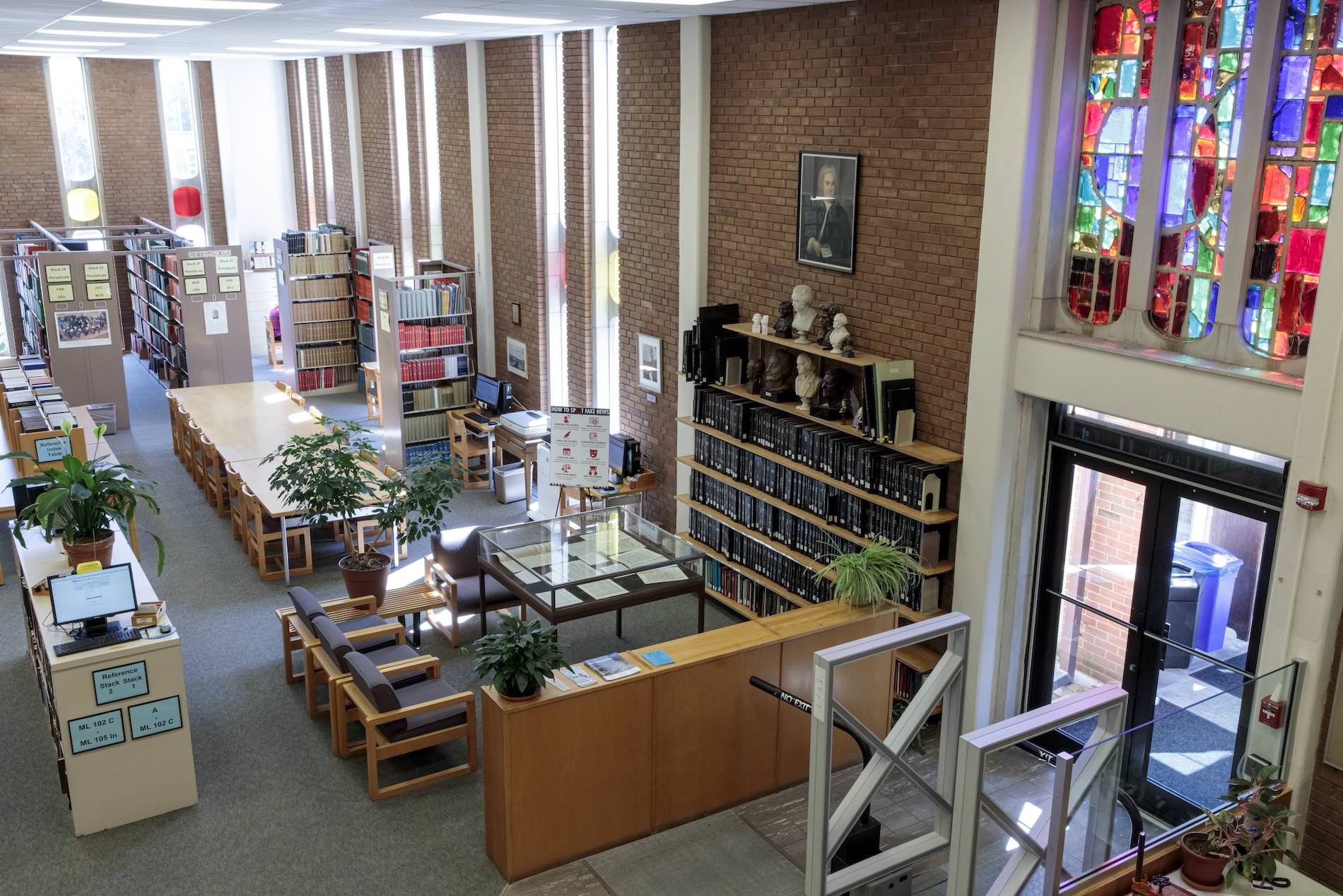 A room with stained glass, book stacks, tables and chairs