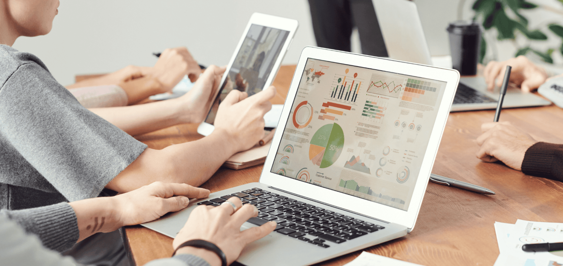 Stock photo of people using laptops with data charts on screens.