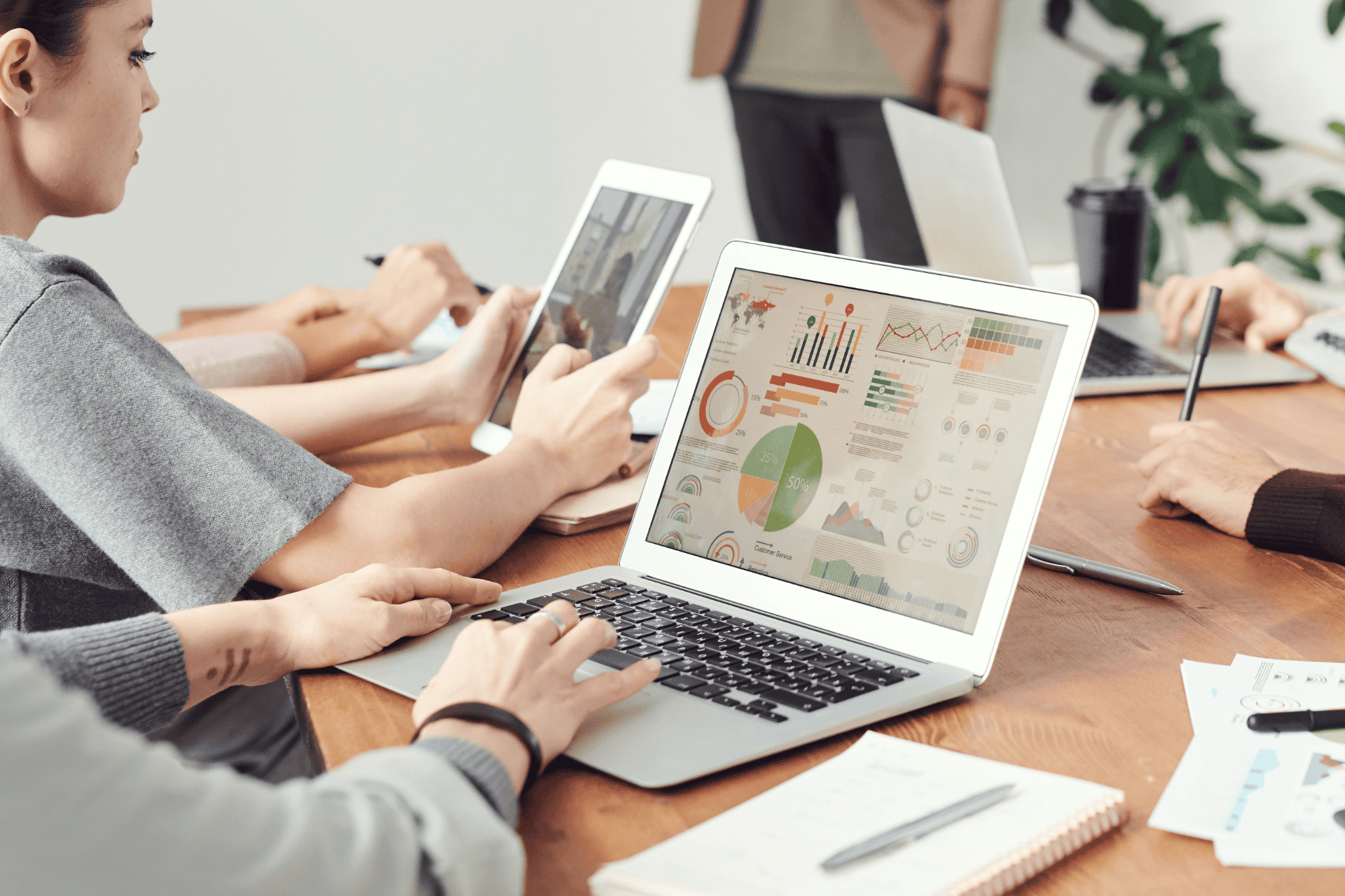 Stock photo of people using laptops with data charts on screens.