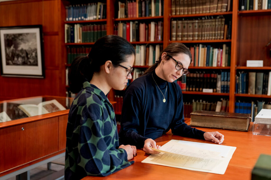 A staff member shows special collections materials to a student.