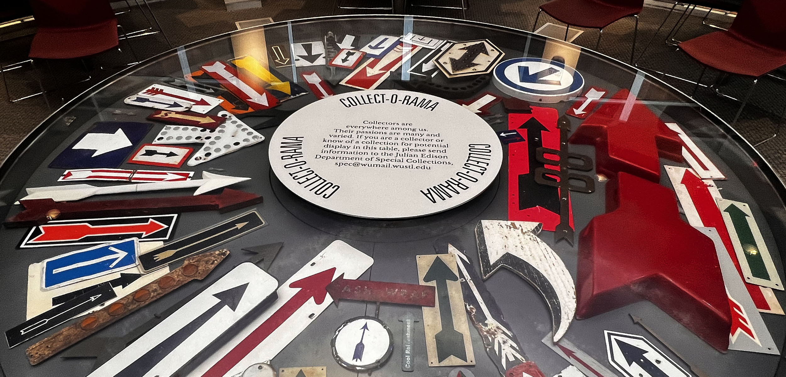 The Collect-O-Rama case in Olin Library with the Me & My Arrow(s) exhibition on display. The exhibition showcases a collection of various arrow signs cultivated over a span of 15 years.