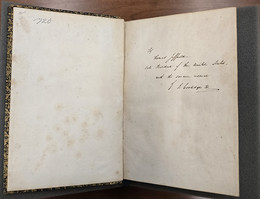 A book opened to its front endpaper with a message written in flowing cursive that reads: To Thomas Jefferson: Late President of the United States, with the sincere respect," signed J. F. Coolidge, Jr.