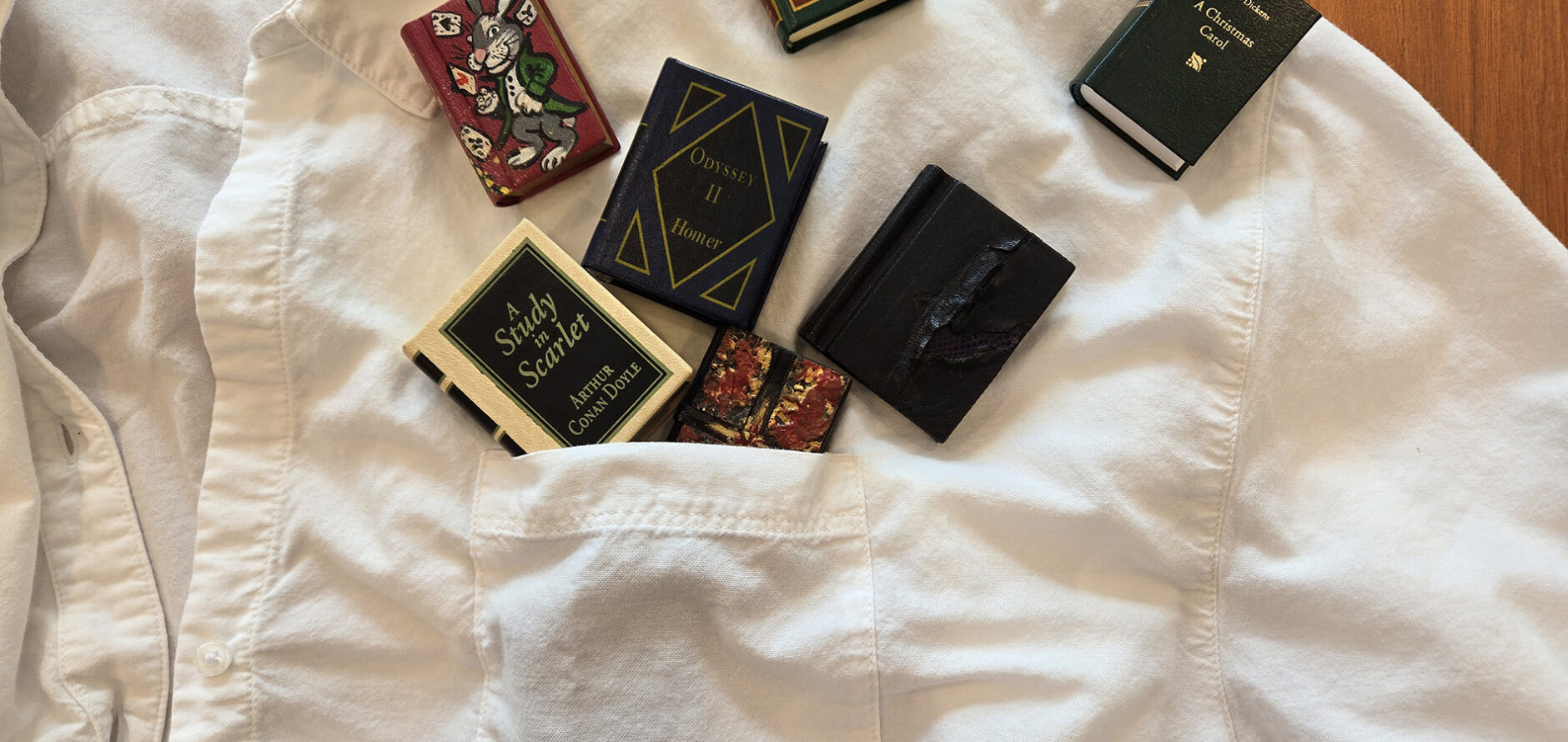 Seven miniature, pocket-sized copies of classic literature displayed on a button-down shirt with a chest pocket to show that the editions are, for a fact, pocket sized.