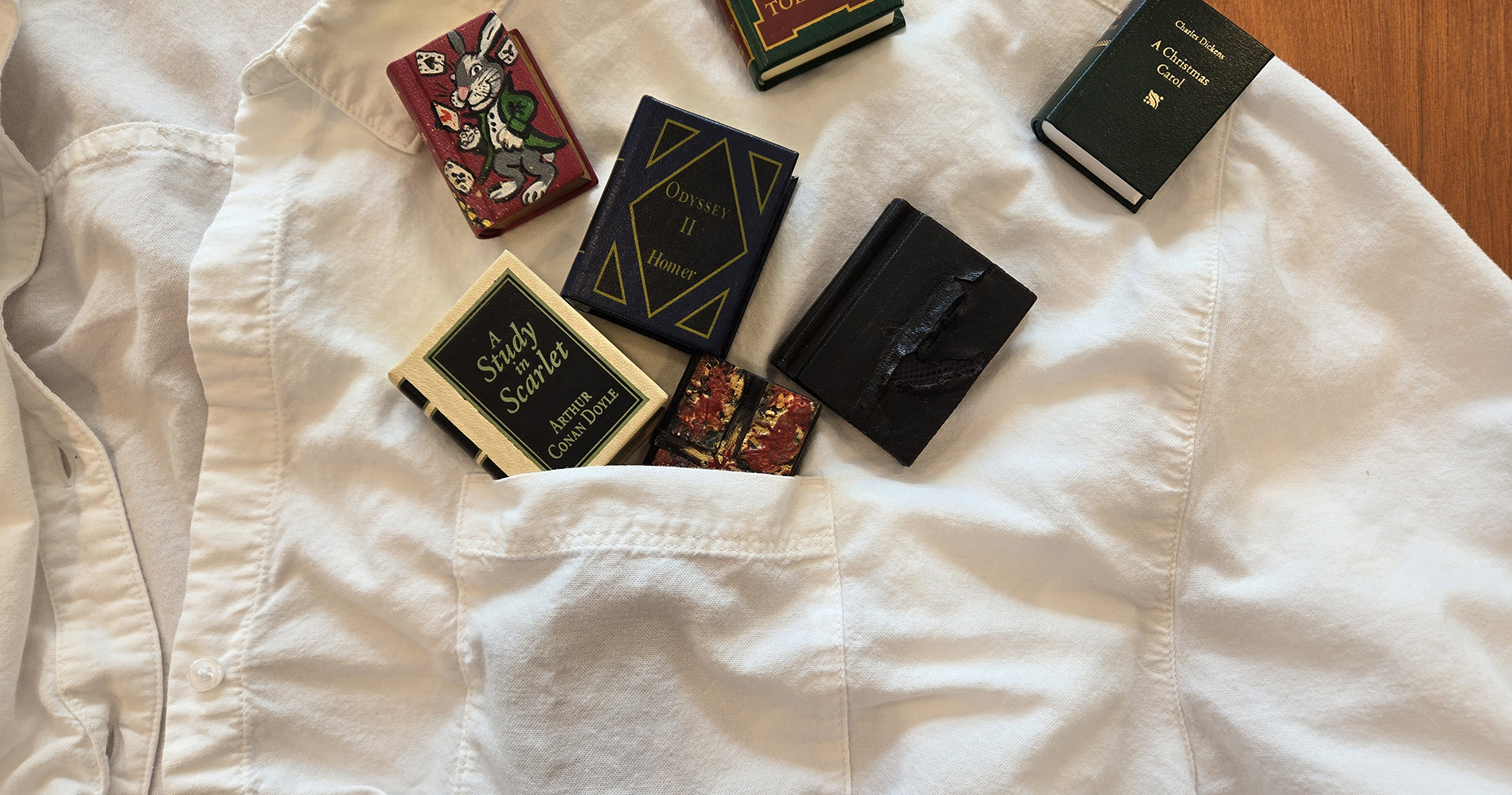 Seven miniature, pocket-sized copies of classic literature displayed on a button-down shirt with a chest pocket to show that the editions are, for a fact, pocket sized.