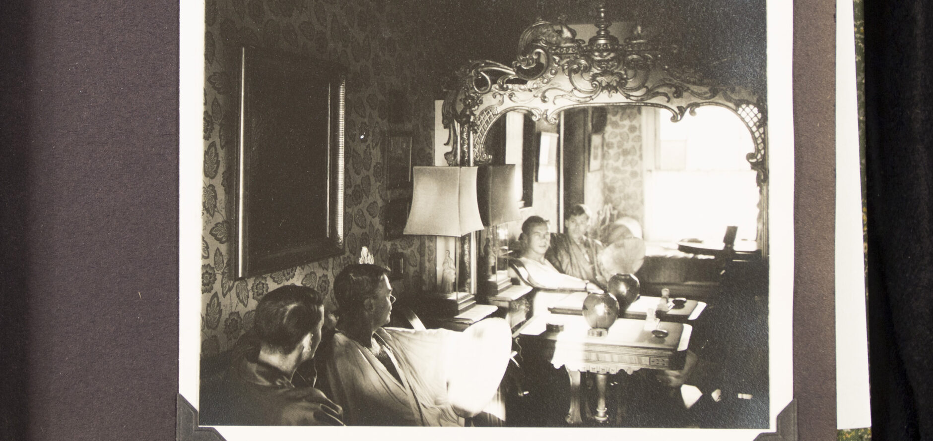 A black-and-white photo of two seated men taken of them looking into a mirror.