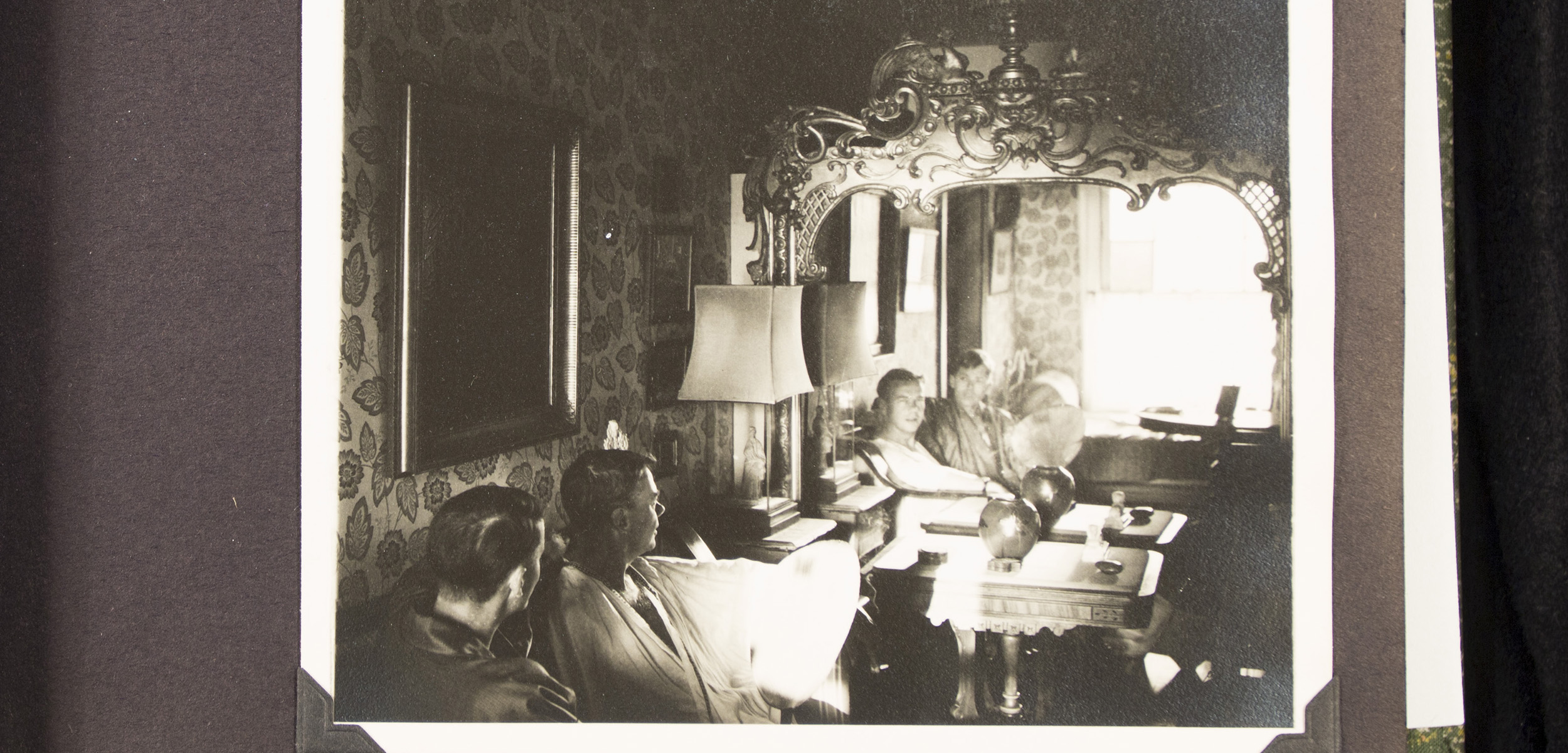 A black-and-white photo of two seated men taken of them looking into a mirror.