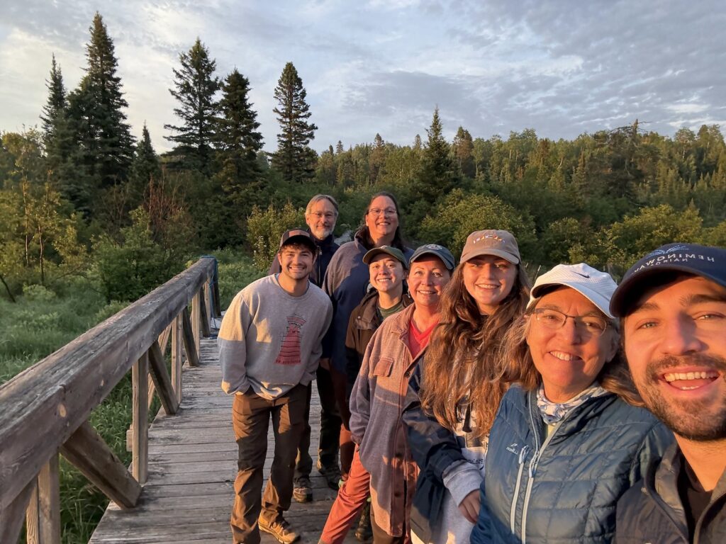 A group of people standing on a wooden bridge surrounded by trees