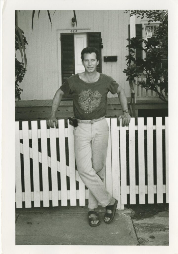 Man in front of a house and a picket fence