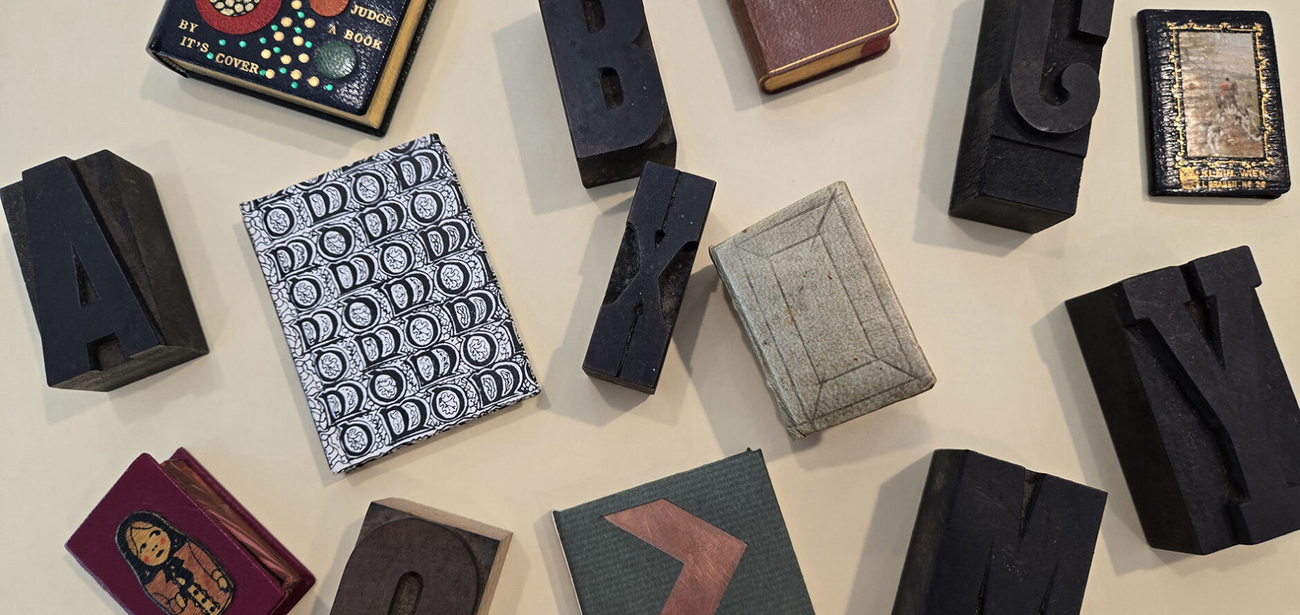 A collection of miniature books and lettered block stamps on a table.