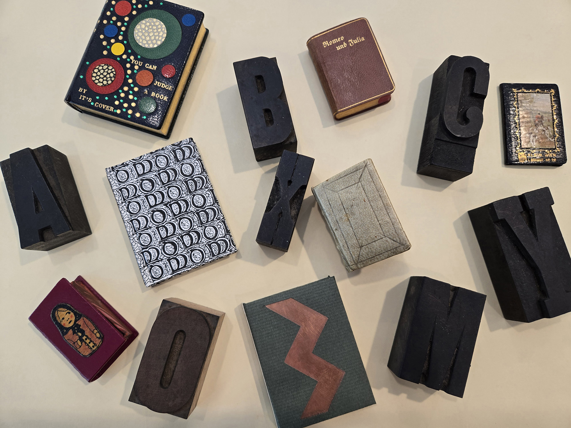A collection of miniature books and lettered block stamps on a table.