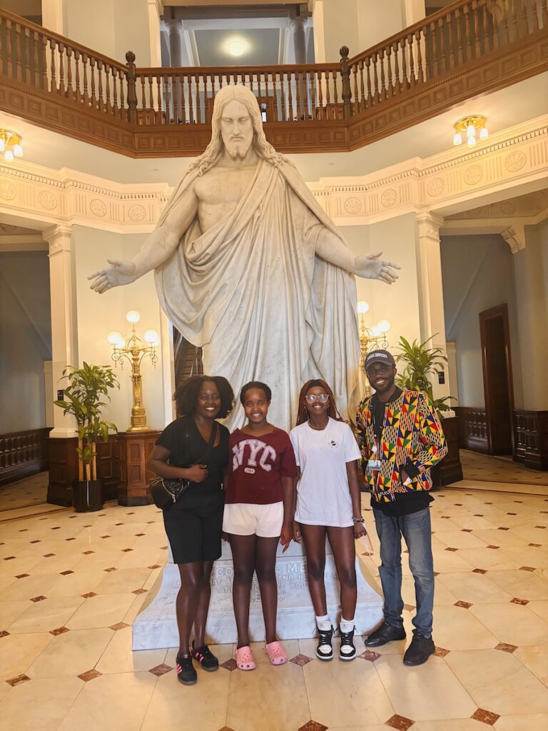 A group of friends stand in front of a large Christ statue
