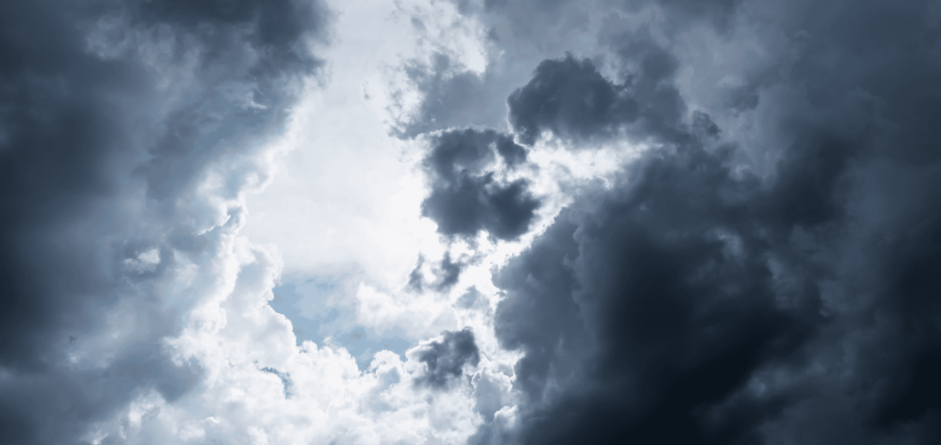 Dark, dramatic storm clouds part to reveal bright sunlight and patches of blue sky.