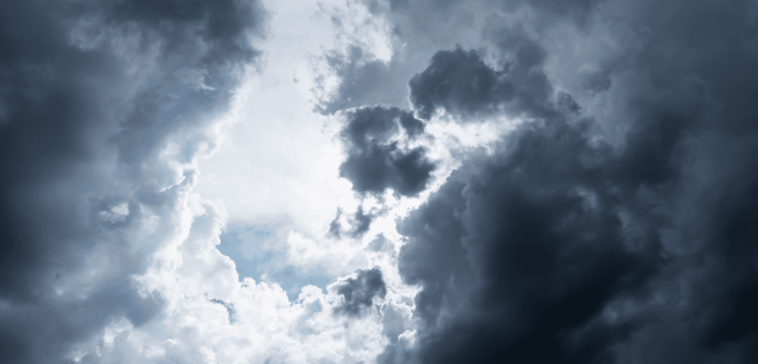 Dark, dramatic storm clouds part to reveal bright sunlight and patches of blue sky.